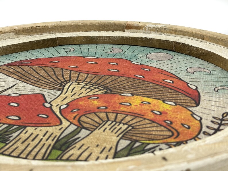 May include: A wooden tray with a circular design featuring three red and orange mushrooms with white spots on a blue and white background with crescent moons.