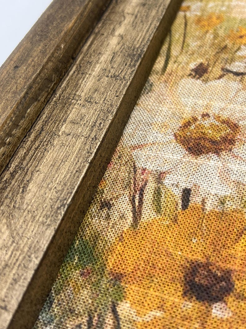 Puede incluir: Primer plano de un marco de madera con acabado dorado. El marco rodea una tela con un patr&oacute;n floral en tonos amarillos, marrones y verdes.