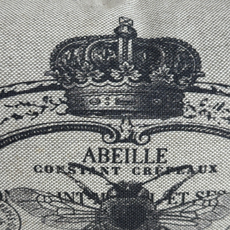 May include: A black and white illustration of a bee with a crown above it. The text "Abeille Constant Crepaux" is printed below the bee.