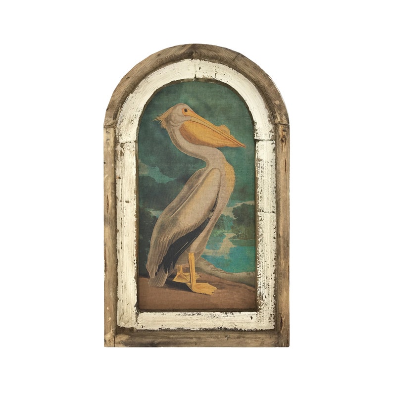 May include: A framed print of a pelican with a white body and yellow beak, standing on a brown surface with a blue and green background.