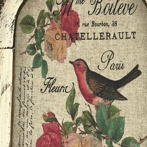 May include: A vintage-style print featuring a robin perched on a branch with pink and yellow roses. The print includes the text "Mme Boileve 38, rue Bourbon, 38 CHATELLERAULT Paris Fleur".