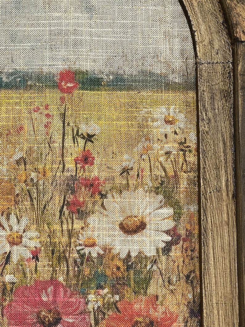 Puede incluir: Un primer plano de una impresi&oacute;n de lienzo enmarcada que representa un campo de flores silvestres. Las flores est&aacute;n pintadas en tonos de rojo, blanco y amarillo, y el fondo es de un verde suave. El lienzo es texturizado, lo que le da un aspecto r&uacute;stico.