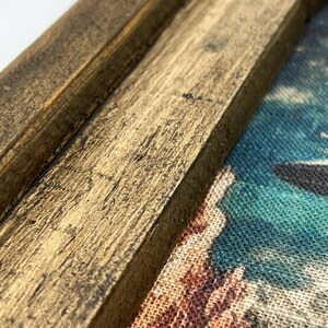 May include: Close-up of a wooden frame with a distressed, brown finish. The frame is partially covering a colorful fabric with a pattern of abstract shapes.