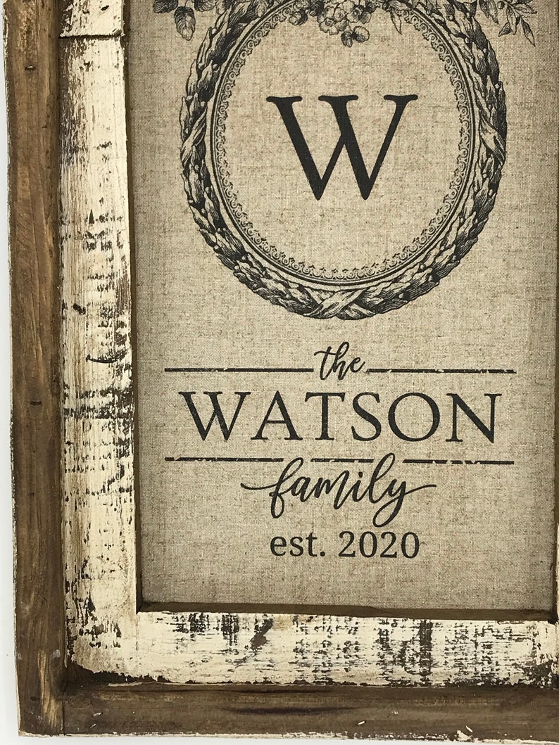 May include: A framed canvas print with a black and white floral design and the letter "W" in a circle. The text "the WATSON family est. 2020" is printed below the design.