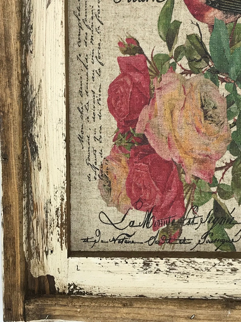 May include: A framed print with a floral design featuring pink and red roses. The print has a vintage aesthetic with a distressed white frame and a handwritten inscription that reads "La Minute Cast Pagnin".