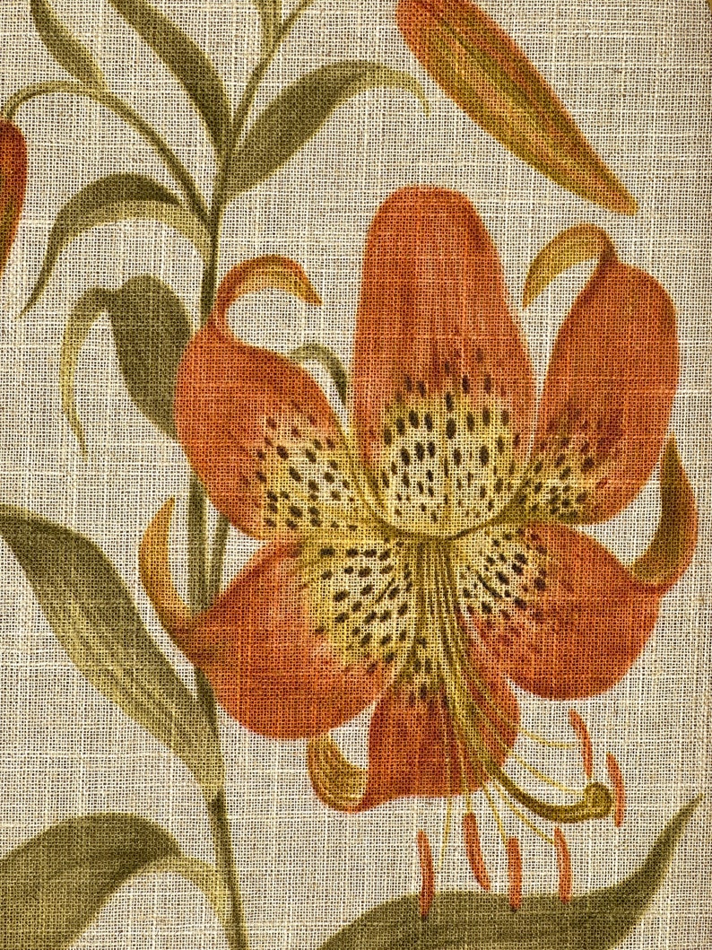 Peut inclure: Gros plan sur une fleur de lys brune et orange avec des taches jaunes et noires sur un fond de lin beige.