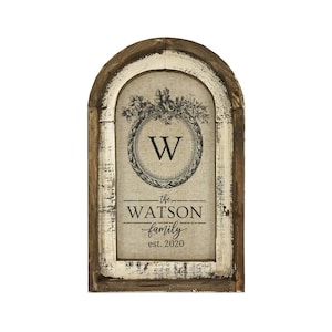 May include: A rustic wooden framed sign with a burlap background featuring a floral wreath with the letter "W" in the center. The text "the WATSON family est. 2020" is printed below the wreath.