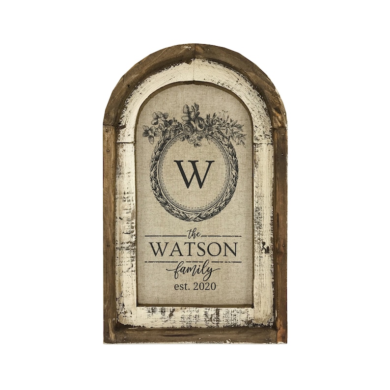 May include: A rustic wooden framed sign with a burlap background featuring a floral wreath with the letter "W" in the center. The text "the WATSON family est. 2020" is printed below the wreath.