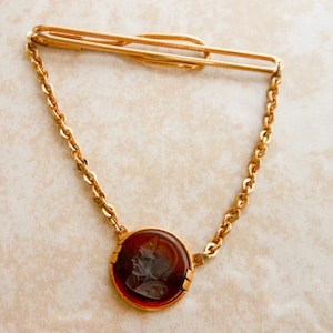 Vintage SWANK goudkleurige dasspeld met ketting en Romeinse soldaat diepdruk carneoolglas – formeel herenaccessoire halverwege de eeuw