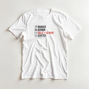 Puede incluir: Una camiseta blanca de manga corta con un estampado gráfico que incluye cuatro iconos cuadrados y el texto MANGER, DORMIR, SALLE DE SPORT y RÉPÉTER. El texto es negro, excepto la palabra SALLE, que está en rojo con un pequeño rayo rojo.