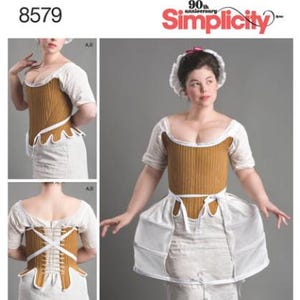 May include: Simplicity pattern 8579 featuring a mustard yellow quilted corset with white trim, worn over a white short-sleeved chemise and a white pannier skirt. The back view shows white lacing. The pattern includes the American Duchess logo.