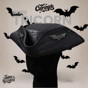 Puede incluir: Un sombrero de tres picos negro con un patrón texturizado de piel de cocodrilo, que presenta un emblema de murciélago negro mate en el lateral. El texto "BATMAN TRICORN" y "Cuirsmith" aparece arriba, con "HAPPY HALLOWEEN" y siluetas de murciélagos.