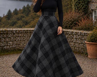 May include: A black long-sleeve ribbed turtleneck sweater paired with a high-waisted, floor-length A-line skirt featuring a dark gray and black plaid pattern. The outfit is completed with black ankle boots with a block heel.