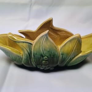 May include: A ceramic bowl shaped like a blooming flower with a glossy finish. The exterior features a gradient of deep forest green at the base transitioning to a bright yellow at the petal tips. The interior is a solid, smooth mustard yellow.
