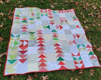 May include: A patchwork quilt with a red border and a variety of fabrics in shades of white, green, and red. The quilt is made up of small squares and triangles, and features a variety of patterns, including polka dots, stripes, and floral prints.