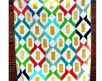 May include: A colorful quilt with a geometric pattern of squares and diamonds in red, green, blue, white, and gold. The quilt is hanging on a brick wall and has the text "Paper Lanterns" at the top and "Four Robbins Designs" at the bottom.