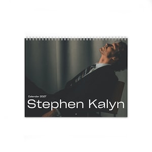 Puede incluir: Un calendario de pared horizontal con una espiral blanca en la parte superior. La portada muestra una fotografía oscura de una persona con traje mirando hacia arriba, con el texto Calendar 2027 y el nombre Stephen Kalyn impresos en blanco.