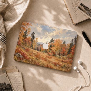 May include: A rectangular laptop skin featuring a detailed landscape painting of an autumn forest with golden, orange, and red foliage, tall evergreen trees, and a cloudy sky. The design includes a central cutout for an Apple logo emblem.