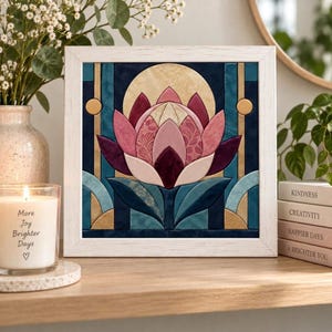 May include: A square framed fabric art piece featuring a central stylized lotus flower in shades of pink, mauve, and deep burgundy. The background consists of geometric teal, navy, and gold fabric panels. The frame is white with a wood grain texture.