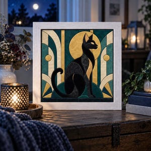 Puede incluir: Una pieza de arte mural cuadrada enmarcada que presenta la silueta de un gato negro estilizado centrado frente a un gran sol circular dorado. El diseño incorpora patrones geométricos en verde azulado oscuro, crema y oro, en un marco de madera blanca.