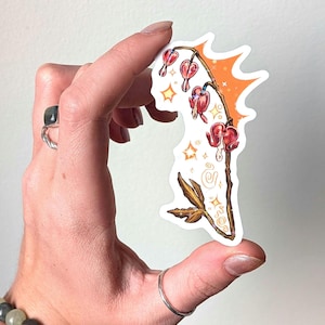 May include: A die-cut sticker featuring a bleeding heart flower stem with red heart-shaped blossoms and green leaves. The design includes an orange background splash, small yellow star accents, and white swirl details on a white adhesive backing.