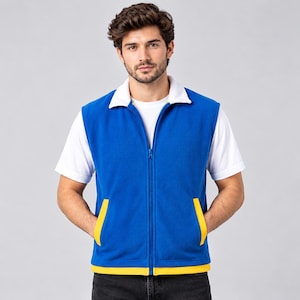 Könnte beinhalten: Eine ärmellose blaue Fleeceweste mit weißem Kragen, durchgehendem Frontreißverschluss und zwei Vordertaschen mit gelben Akzenten. Die Weste wird über einem schlichten weißen T-Shirt mit kurzen Ärmeln getragen und erzeugt einen farbenfrohen Kontrast.