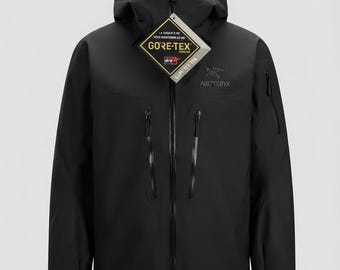 May include: A black Arc'teryx hooded jacket featuring a full-length front zip, two vertical chest pockets with black zips, and a sleeve pocket. A diamond-shaped Gore-Tex tag is attached to the front zip pull, displaying the Gore-Tex logo.