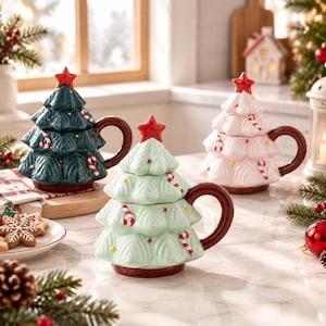 Pode incluir: Três canecas de cerâmica em forma de árvore de Natal com tampa. Cada caneca apresenta um design verde-escuro, verde-claro ou branco com uma estrela vermelha no topo, pequenos pontos coloridos e detalhes de bengalas doces e alça castanha.