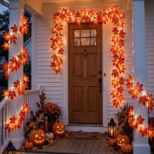 May include: A front porch decorated with illuminated maple leaf garlands draped around white pillars and a wooden door. Several carved jack-o'-lanterns with glowing interiors are arranged on the wooden steps alongside lanterns and autumn foliage.