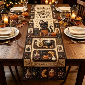Puede incluir: Un camino de mesa rectangular de tela con temática de Black Cat Potion Cafe, con ilustraciones de un gato con sombrero, pociones, pasteles y tazas de café. El texto dice Black Cat Potion Cafe, witchy brews & treats y A LITTLE MAGIC IN EVERY CUP.