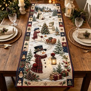 May include: A quilted fabric table runner featuring a winter scene with multiple snowmen, pine trees, a small cabin, and wrapped gifts. The design includes a snowman wearing a black top hat and a red plaid scarf holding a lit lantern.