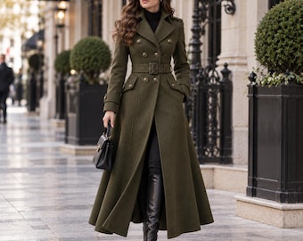 May include: An olive green double-breasted long coat featuring a notched lapel, a matching waist belt with a buckle, and gold-toned buttons. The coat is worn over a black turtleneck, black trousers, and black knee-high leather boots.