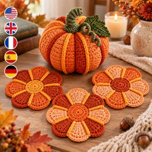 May include: A crocheted orange pumpkin with a green stem and leaf, accompanied by three matching flower-shaped crocheted coasters in shades of orange, yellow, and rust. The items feature intricate yarn textures and are arranged on a wooden surface.
