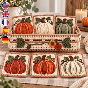 May include: A rectangular crochet basket with a lattice pattern and a vine motif, containing three square crochet coasters featuring pumpkins in orange, cream, and green. Three matching pumpkin coasters are arranged in front of the basket.