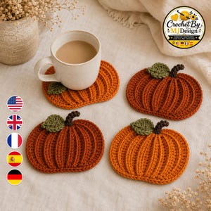 May include: Four pumpkin-shaped crochet coasters in shades of orange, each featuring a dark brown stem and a single green leaf. One coaster supports a beige ceramic mug filled with a light brown beverage. A logo in the corner reads Crochet By MJDesign.