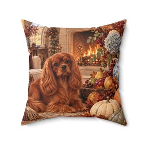 May include: A square throw pillow featuring a printed image of a brown Cavalier King Charles Spaniel lying down. The scene includes a fireplace with a fire, a bowl of assorted fruits like pears and apples, and pumpkins on the floor.