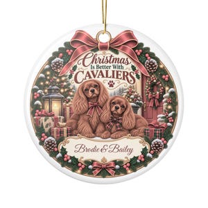 Puede incluir: Un adorno navideño redondo de cerámica blanca con dos perros Cavalier King Charles marrones, un farol, regalos y una corona. El texto dice "Christmas Is Better With CAVALIERS" y "Brodie & Bailey" con un cordón dorado para colgar.