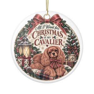 Peut inclure: Une décoration de Noël ronde en céramique blanche représentant un épagneul Cavalier King Charles brun couché sur un coussin à carreaux. Le motif inclut une lanterne, des cadeaux, des branches de pin et un nœud rouge avec le texte All I Want for CHRISTMAS IS MY CAVALIER.