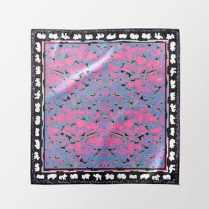 Puede incluir: Un pañuelo cuadrado con un patrón central de formas abstractas en rosa vibrante y azul. El pañuelo está enmarcado por un borde negro grueso decorado con un patrón repetitivo de siluetas blancas de varios animales y criaturas.