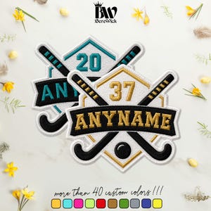 May include: Two embroidered patches featuring a shield shape with crossed field hockey sticks and a ball. One patch has gold text reading 37 and ANYNAME, the other has teal text reading 20 and ANYNAME. Both have black sticks and white backgrounds.