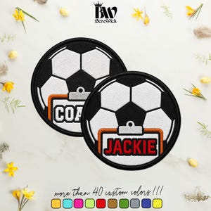 May include: Two circular embroidered patches featuring a black and white soccer ball pattern. One patch displays a clipboard with the text COACH in white, and the other displays a clipboard with the name JACKIE in red letters on a white background.