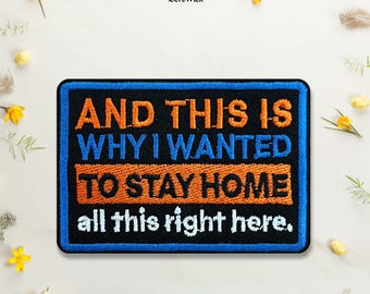 May include: A rectangular embroidered patch with a black background and a blue border. The text reads: AND THIS IS WHY I WANTED TO STAY HOME, with the words TO STAY HOME on an orange background, and all this right here in white text.