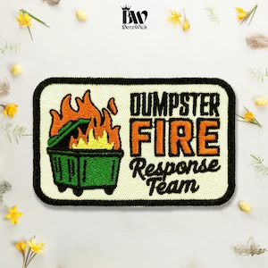 May include: A rectangular embroidered patch with a black border on a cream background. It features a green dumpster engulfed in orange and yellow flames on the left, with the text DUMPSTER FIRE Response Team in black and orange on the right.