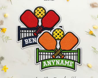 Puede incluir: Dos parches bordados con palas de pickleball cruzadas y una pelota amarilla sobre una red. Un parche tiene palas rojas con el nombre BEN, el otro tiene palas naranjas con el nombre ANYNAME. El texto dice BereWick y más de 40 colores personalizados.