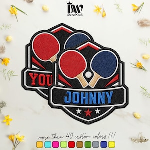May include: Two embroidered patches featuring a red and a blue table tennis paddle with a white ball. The design includes a black shield background, red and white accents, and the name JOHNNY in blue text. The BereWick logo is at the top.