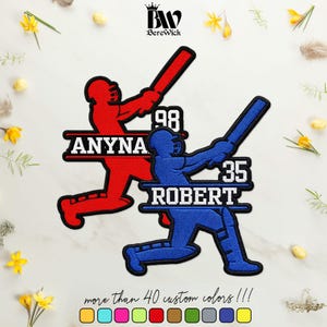 May include: Two embroidered baseball player patches, one red and one blue, each featuring a silhouette of a batter swinging a bat. The red patch displays the name ANYNA and number 98, while the blue patch shows the name ROBERT and number 35.