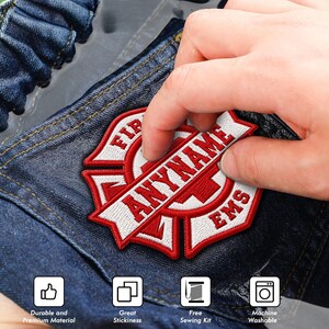 May include: A red and white embroidered patch featuring a Maltese cross design with the text ANYNAME and EMS. The patch is applied to dark blue denim fabric. Four square icons at the bottom indicate durable material, stickiness, sewing kit, and washability.