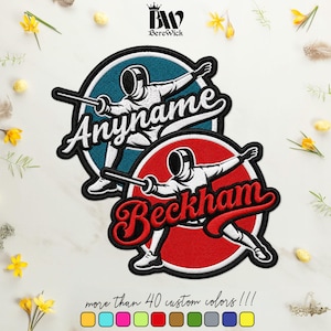 Peut inclure: Deux écussons brodés circulaires représentant un escrimeur en uniforme blanc tenant un fleuret. Un écusson a un fond bleu avec le texte Anyname, et l'autre a un fond rouge avec le texte Beckham. Le logo BereWick est situé en haut.