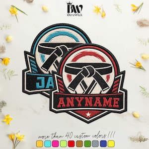 May include: Two circular embroidered patches featuring a black martial arts belt tied in a knot at the centre. One patch has blue accents with the text JA, and the other has red accents with the text ANYNAME. The BereWick logo is at the top.