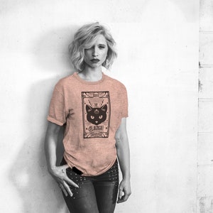 May include: A woman wearing a pink t-shirt with a black cat tarot card graphic. The card reads "XIII The Blackcat - Shadow Path".